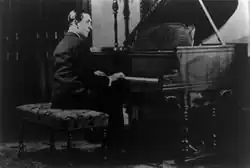 A man seated at a piano with his hands on the keyboard.