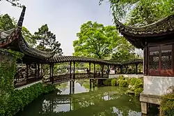A Chinese garden with a bridge over a pond and pavilions on both sides