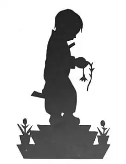 Silhouette of a young boy looking down as he holds a wilting flower