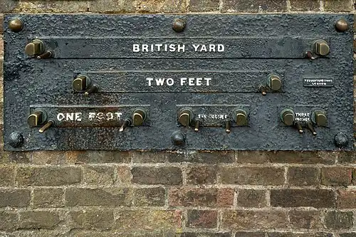 Imperial standard lengths on the wall of the Royal Observatory, Greenwich, London – 1 yard (3 feet), 2 feet, 1 foot, 6 inches (1/2-foot), and 3 inches. The separation of the inside faces of the marks is exact at an ambient temperature of 60 °F (16 °C) and a rod of the correct measure, resting on the pins, will fit snugly between them.