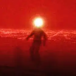 Man sitting in front of Phoenix, Arizona's cityscape with a light obscuring the face, with a predominant red hue.