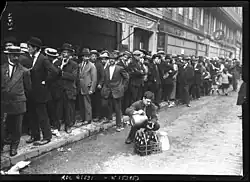 Queue of men along a sidewalk.