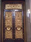 Bronze doors, designed by Cockerell, 12 feet (4&nbsp;m) 8 inches (20&nbsp;cm) high by 6 feet (2&nbsp;m) 4 inches (10&nbsp;cm) wide and weighs 74 cwt, there are three on each side of the hall, also three similar doors at the south end lead to the Crown Court and a smaller one is beneath the organ.