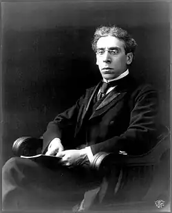 Black-and-white photo of Zangwill wearing a suit, tie, and glasses