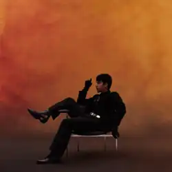 The cover artwork for Mirada; a man is seen, in dark attire, sitting in a chair upon a red-yellow gradient background.