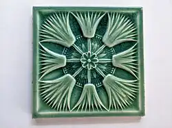 Blue green tile with a radial pattern of four flower heads
