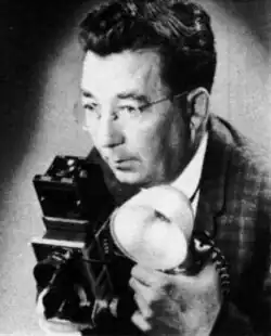 Black-and-white head shot of Beers facing left and holding a camera