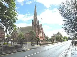 a red sandstone church with a tall spire and a large pointed arch window