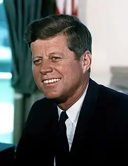 President Kennedy smiling and sitting in the Oval Office