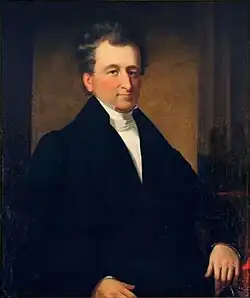 Half-length portrait of sitting Leamy in suit.