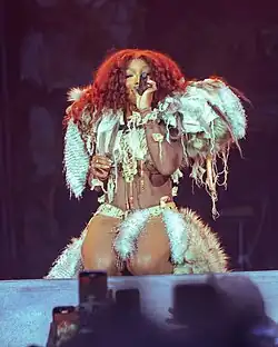 SZA performing while kneeling in front of the stage close to the crowd