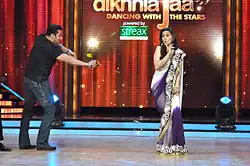 A man poses to hit a woman with a slingshot on the sets of a television show.