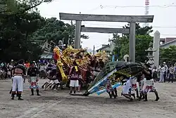 Men manipulating a decorative model of a boat and a whale.