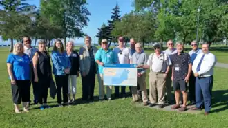 People posing for an outdoor group photo and holding a map