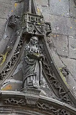 At the top of the gable is this statue depicting a saint reading a book.