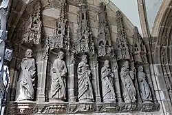 The apostles in the porch interior. As a consequence of the damage to the statues during the turmoil of the French revolution not all of the apostles can be identified. On the eastern side on the left as one enters the porch, the first apostle can be identified as Saint Peter, the third apostle is James the Major, the fourth is James the Lesser and the fifth is Saint John who holds a chalice and is beardless. On the other side only Saint Andrew is identifiable with his distinctively shaped cross. Note the elaborate canopy above each of the niches containing the apostles and the carvings on the platforms upon which they stand.