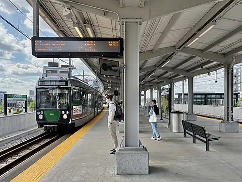 A light rail train at an elevated station in an urban area