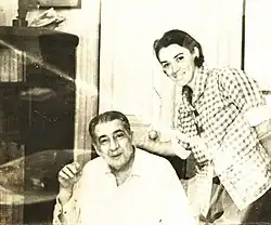 A young Tania Díaz Castro stands next to José Lezama Lima, seated