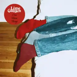 A photograph of two people's legs and feet, wearing jeans and different coloured socks, at the end of a bed