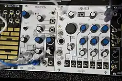 A white panel that is covered with various blue and white dials, wires and empty sockets