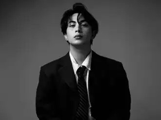 black-and-white posed photo of Ralph William Datoon (Maki) wearing a light shirt and dark suit with tie, looking directly at camera with serious countenance