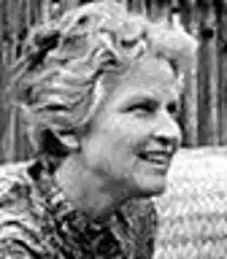 Black and white profile Press shot of a smiling, young, blonde woman with short, curly hair.