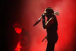 A picture of a man singing into a microphone and a man playing a guitar on a stage