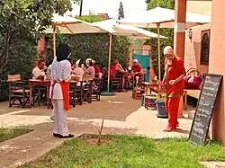 Trainees serving customers who are seated outside under umbrellas