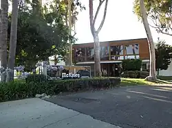 Front of an office with trees and bushes. A sign reads "McKinley Elevator/Equipment Corporation".