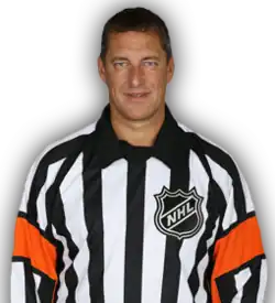 Middle-aged man wearing a black and white vertically striped shirt, with orange arm bands, and the National Hockey League crest