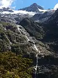 The Hirere Falls on the Milford Track are on the south western extreme of the Wick Mountains. The peaks behind at up to 1,920 metres (6,300&nbsp;ft) do not have official names.[1]