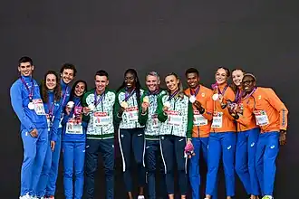 Photo of twelve athletes in tracksuits with medals around then necks