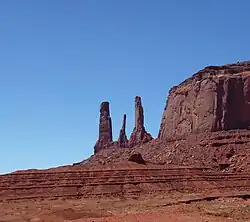 Angled skirts of Organ Rock, at base of De Chelly Sandstone vertical massive cliffs