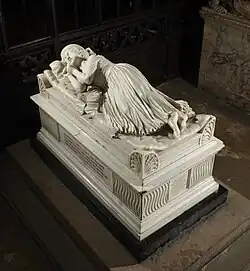 This image shows the famous monument to five-year-old Penelope Boothby by Thomas Banks (1793) at Ashbourne, Derbyshire, which marked a significant turning point in English funerary sculpture. The monument depicts the child lying peacefully asleep on a mattress atop an elaborately carved tomb chest, her head resting on a pillow with her hands positioned naturally by her side. Banks's revolutionary approach portrays death as gentle sleep rather than the traditional rigid formality of earlier monuments, reflecting the Romantic movement's view of children as embodiments of purity and innocence. The white marble effigy demonstrates exceptional technical skill in the rendering of the flowing nightgown and soft bedding, whilst the tomb chest below features Gothic Revival detailing including tracery panels. This monument initiated a fashion for sentimental children's monuments that continued throughout the Victorian period, fundamentally changing how childhood death was commemorated in English churches. The work represents a masterpiece of neoclassical sculpture and one of the most moving examples of funerary art from this period.