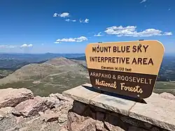 The United States Forest Service sign at the summit of Mount Blue Sky with the following inscription: "Mount Blue Sky Interpretive Area Elevation 14,130 feet Arapaho & Roosevelt National Forests."