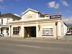 A one-storey building with a sign reading AD 1906. A smaller sign on the building reads "Mitsubishi Electric"