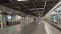 The station's concourse with faregates on the left leading to the platforms. Information displays and signage are visible, providing directions and other details to commuters.