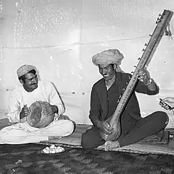 Two Afghan musicians playing a zerbaghali drum (left) and a tanbur (right).