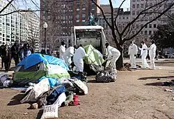 multiple National Park Service workers deposit a tent into a garbage truck