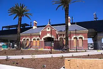 The old heritage station is placed in front of the new black rail bridge.