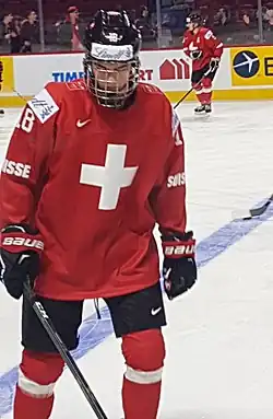 Hockey player dressed in a red jersey with a white cross as the logo