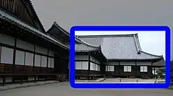 Wooden building with a large hip-and-gable roof, white walls and wooden sliding doors.