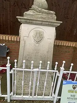 The club's cenotaph can be seen with a fence in the background, the names of all players who died serving in the armed forces are displayed on the front of the light coloured stone memorial..