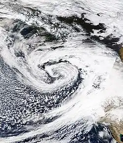 Satellite image of the Western United States and Pacific Ocean. The October 2021 bomb cyclone is visible as a comma-shaped formation of clouds off the west coast of North America.
