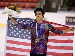 A photograph of Nathan Chen posing with the American flag.