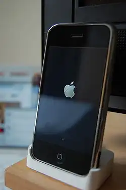 The original iPhone is standing in a small docking station.