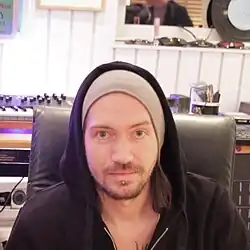 Oscar Holter wearing a grey beanie and a black hoodie while sitting in a music studio.