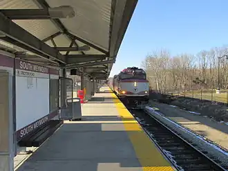 A passenger train pulling into a suburban station with a high-level platform