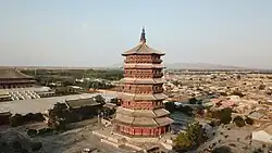A multi-storey wooden pagoda with houses in the background