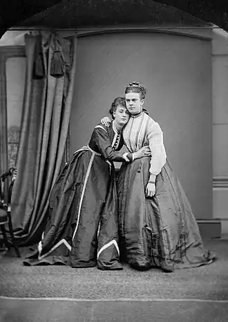 Park and Boulton hug, both wearing Victorian ladies dresses